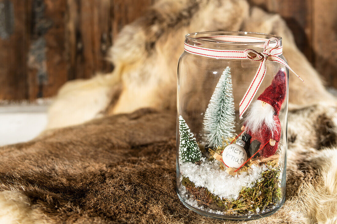 A glass filled with fir trees and an elf, as a Christmas decoration