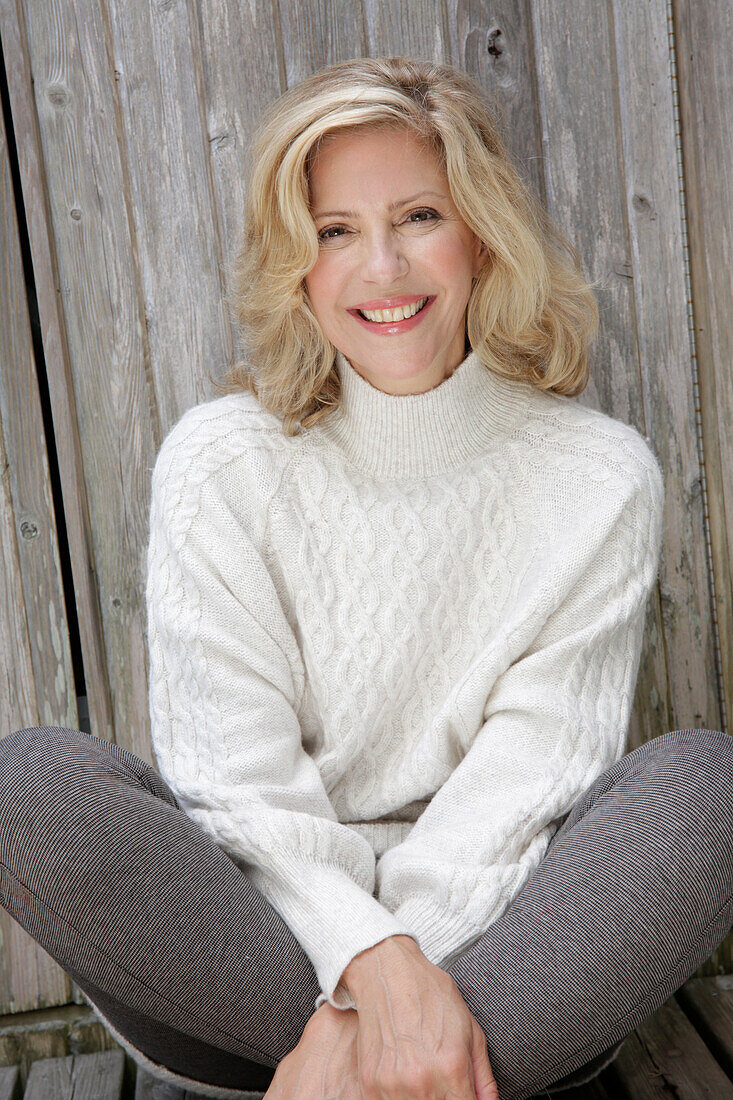 Mature blonde woman in white knitted jumper and grey leggings