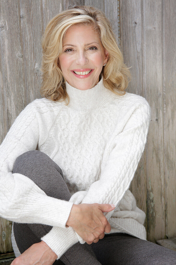 Mature blonde woman in white knitted jumper and grey leggings