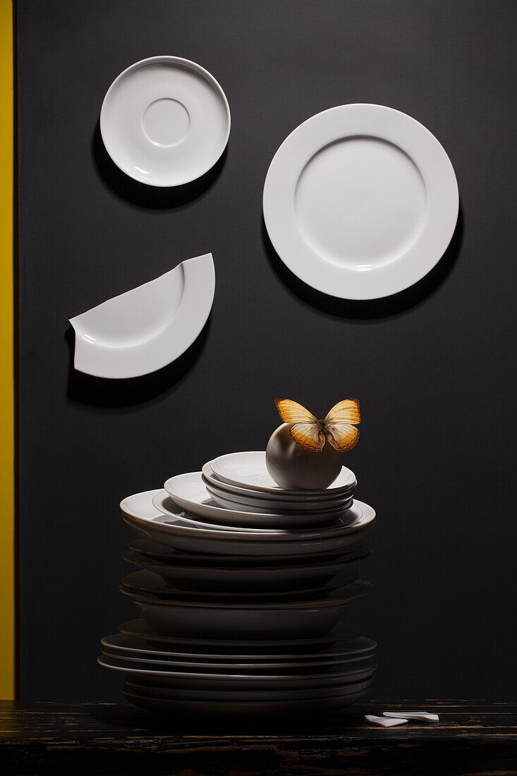 White plates and pile of plates with a butterfly on black background