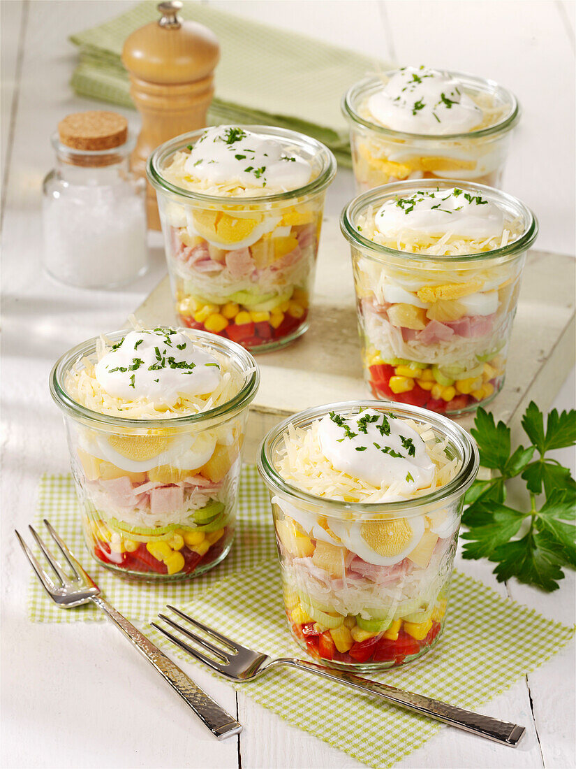 Layered salad in a glass with egg, ham, and cheese
