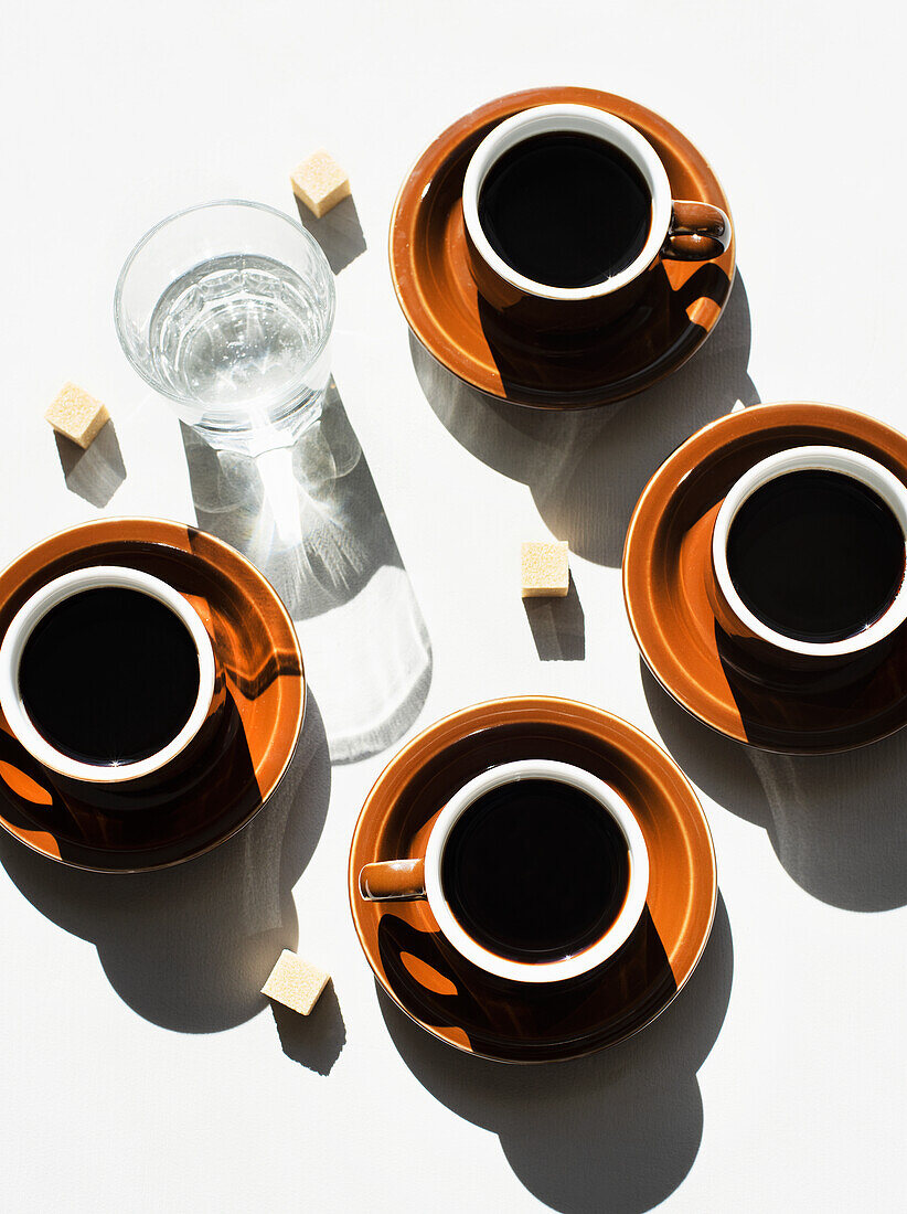 Vier Espresso in Tassen und ein Glas Wasser