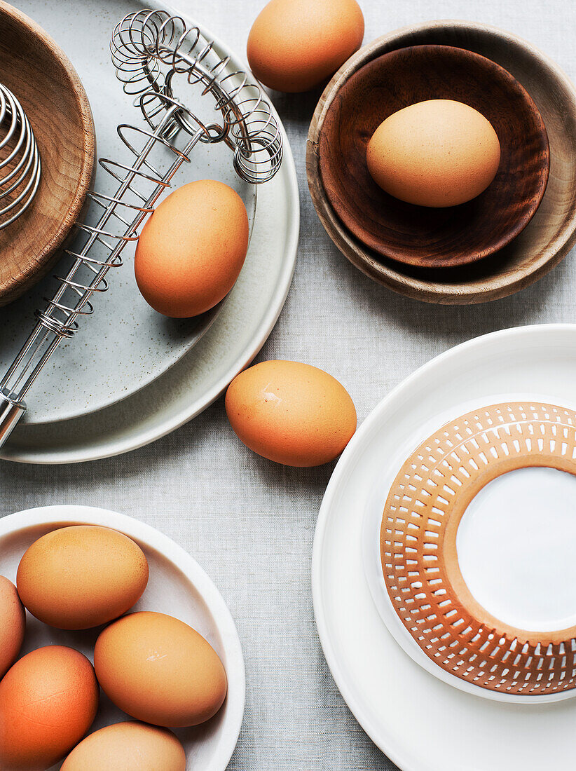 Brown eggs, plates, bowls and egg beater