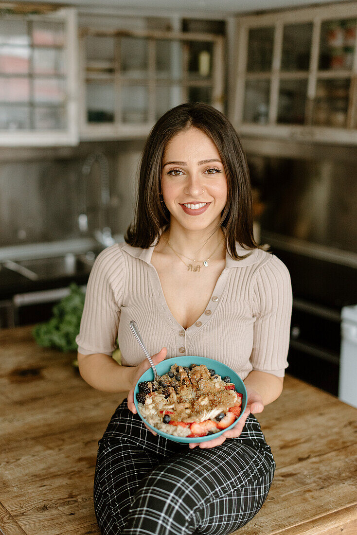 Smiling young woman holding granola bowl