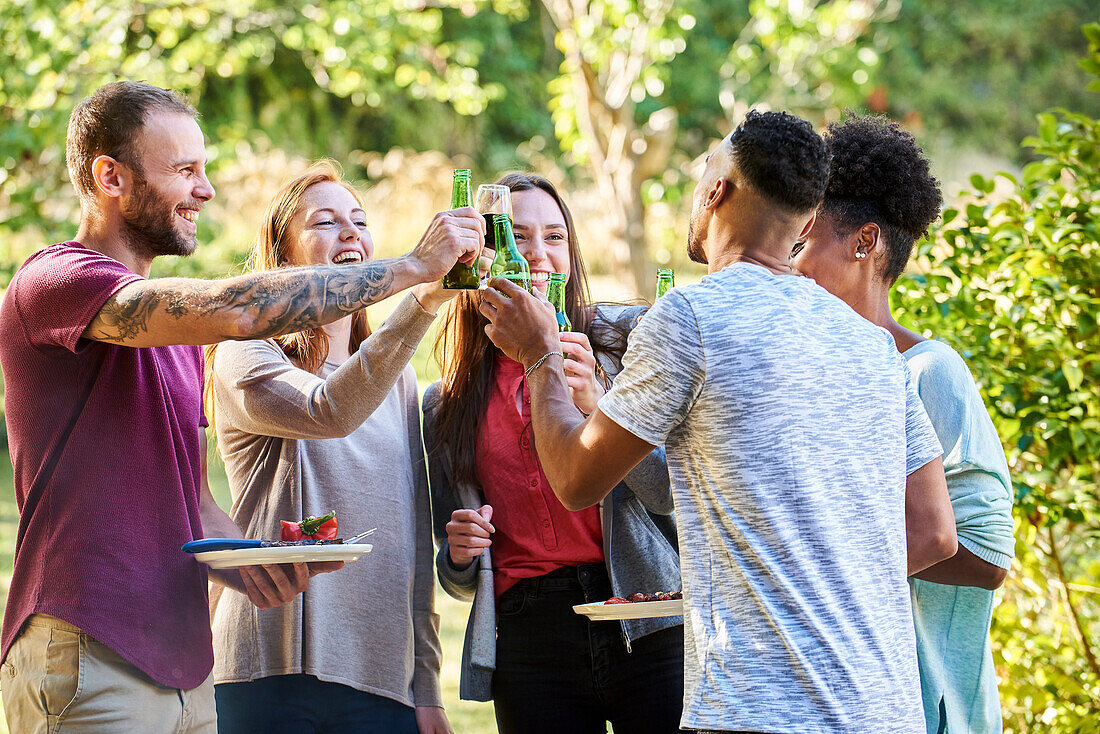 Happy young friends toasting drinks in garden