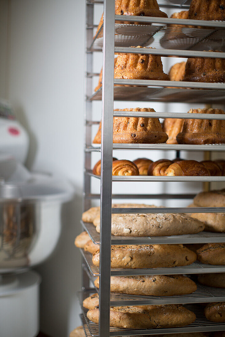 Shelf with bundt cakes, croissants, and loaves of bread in a bakery