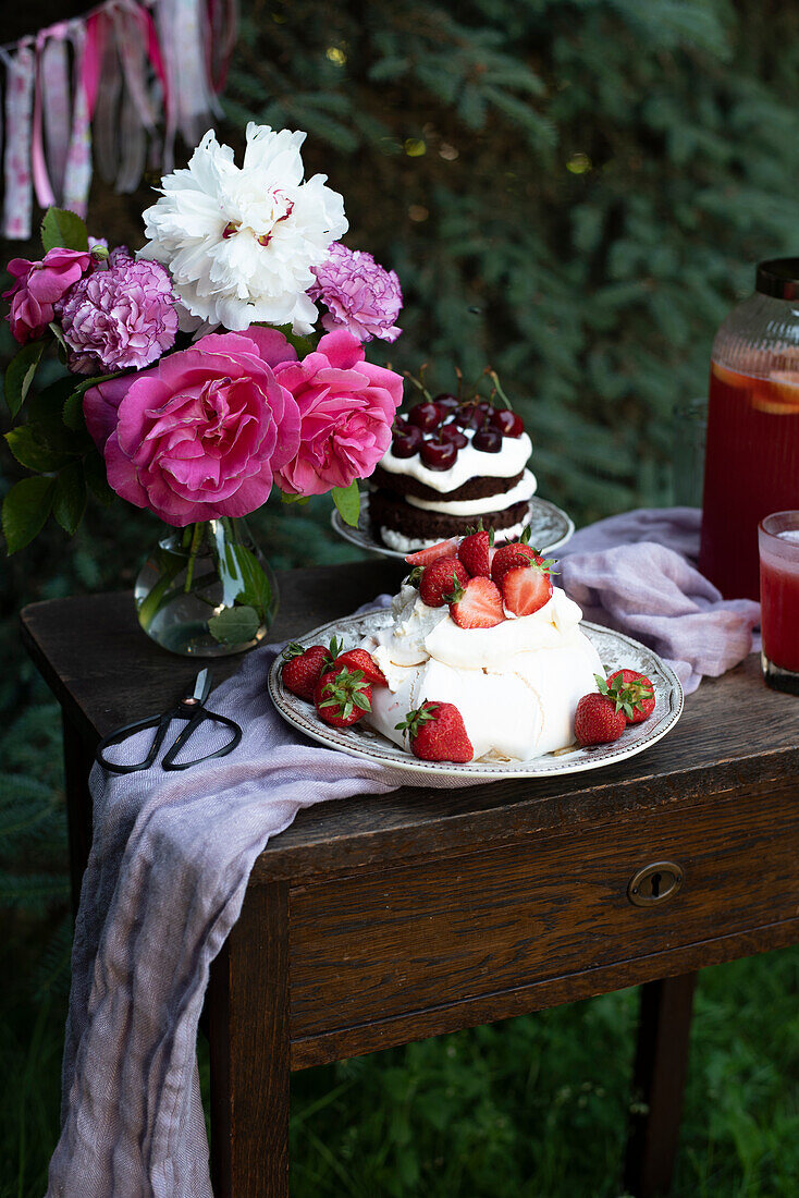Pavlova-Torte mit Mascarponecreme und Erdbeeren dahinter Mini Schwarzwälder Kirschtorte