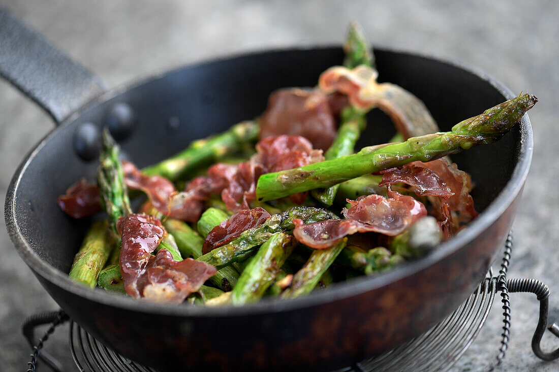 Grüner Spargel mit Speck in der Pfanne