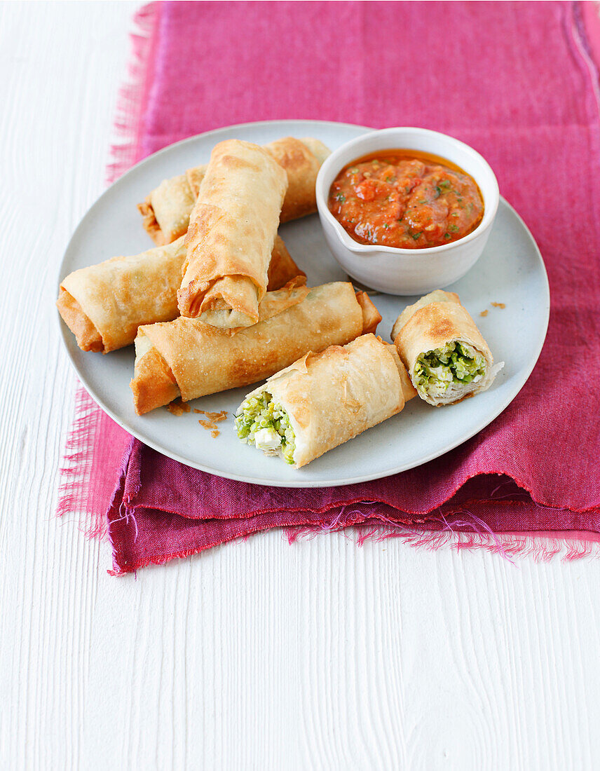 Spring rolls filled with quinoa, peas, and feta served with tomato sauce
