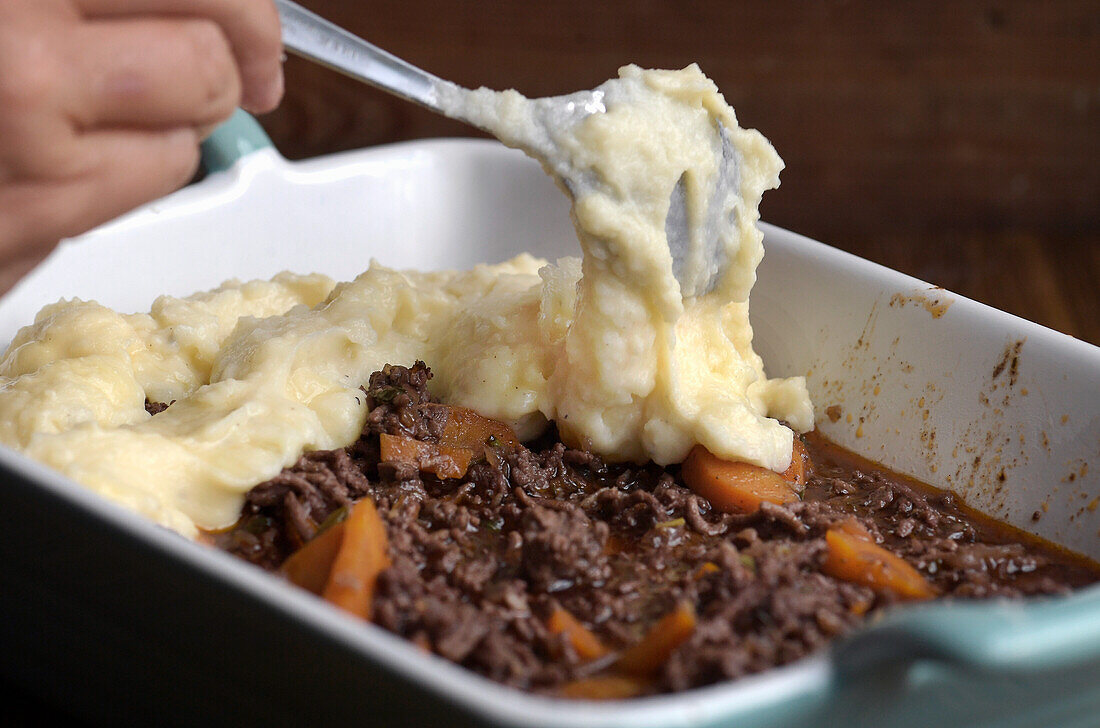 Preparing Shepherds Pie: spreading mashed potatoes over the mince mixture