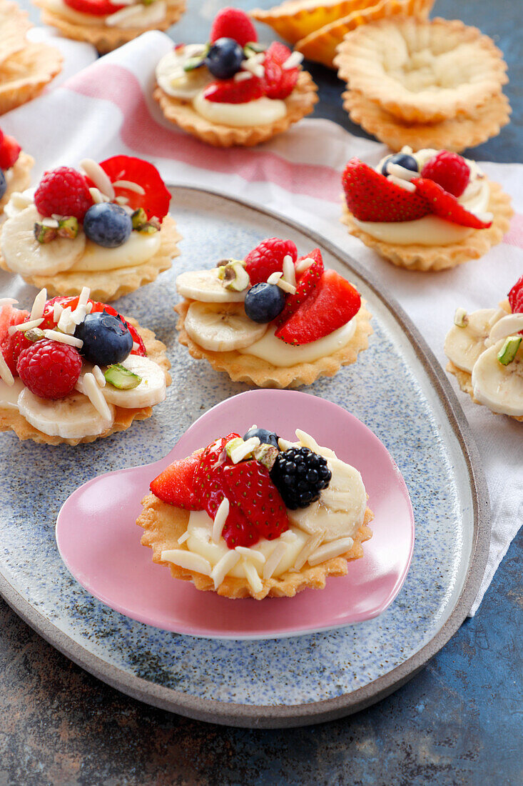 Torteletts mit Pudding, frischem Früchten und Mandeln