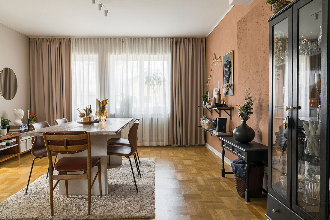 Schwarzer Vitrinenschrank und Konsole, in der Mitte Tisch mit Lederstühlen im Esszimmer mit rostbrauner Wand