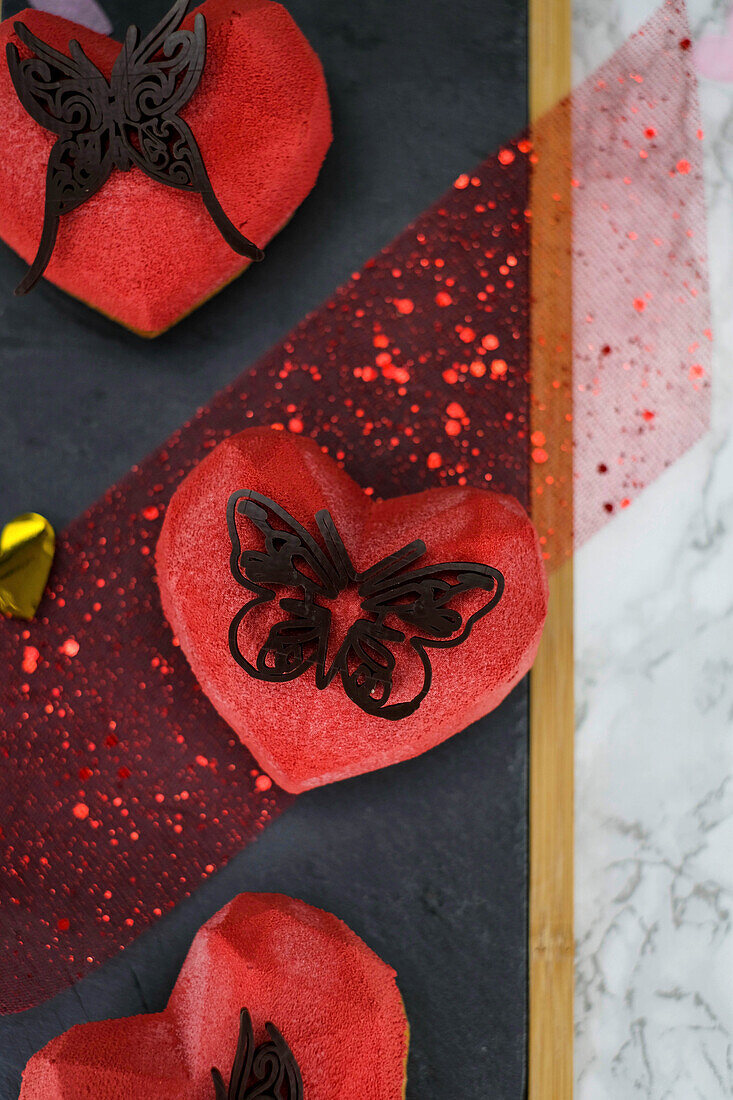 Herzförmige Johannisbeertörtchen dekoriert mit Schokoladenschmetterling