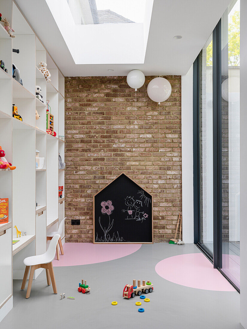 Kinderspielraum mit raumhohem Regal, Backsteinwand und Glasschiebetür