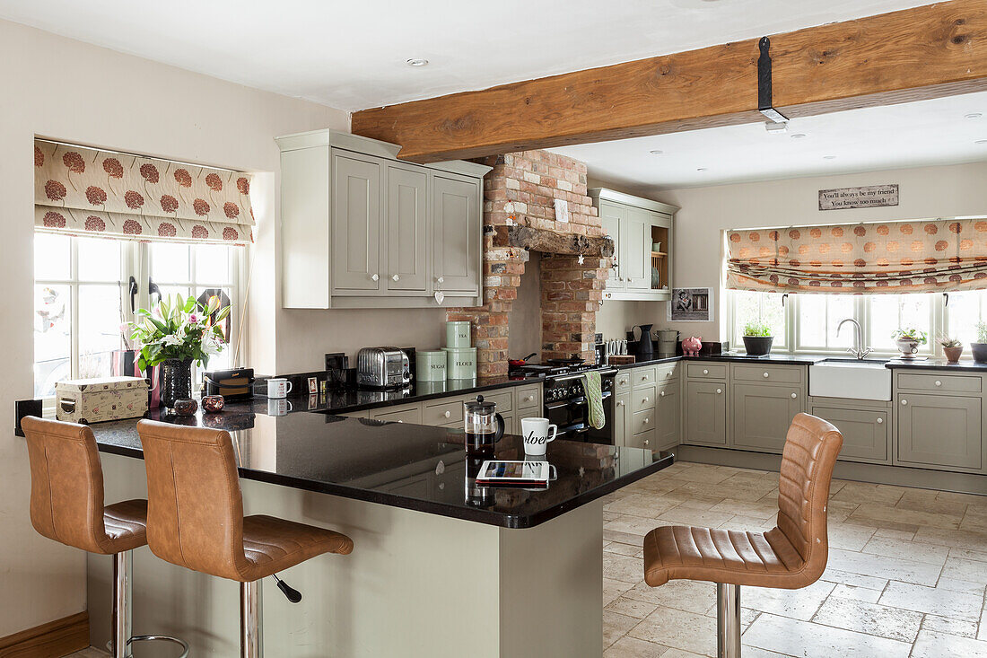 Bright fitted kitchen cabinets across the corner in a country style, kitchen peninsula counter with bar stools