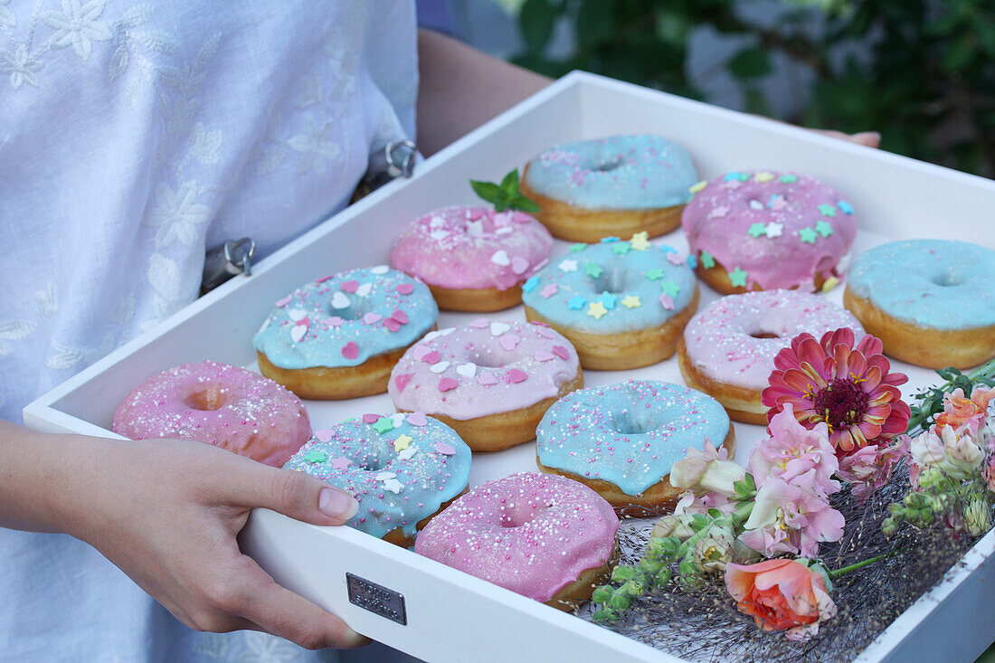 Bunte Donuts mit pastellfarbener Zuckerglasur auf Holztablett