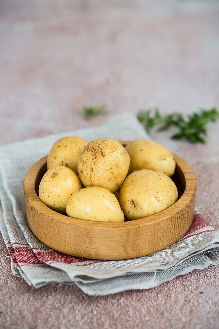 Raw uncooked potatoes in a wooden bowl