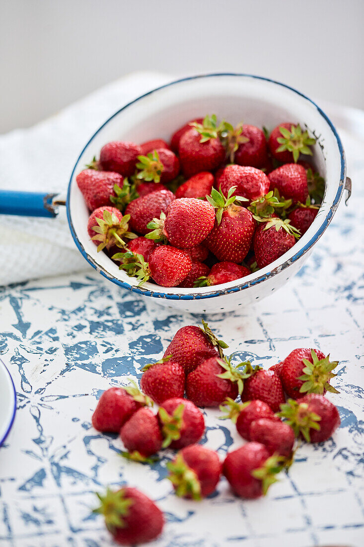Frische Erdbeeren für Erdbeermarmelade auf Tisch und in Emaillesieb