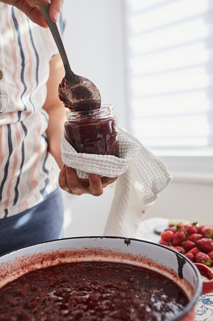 Heiße Erdbeermarmelade in ein Glas füllen