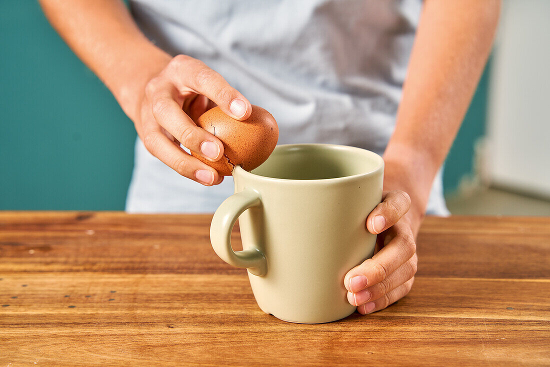 Cracking an egg on the rim of a cup