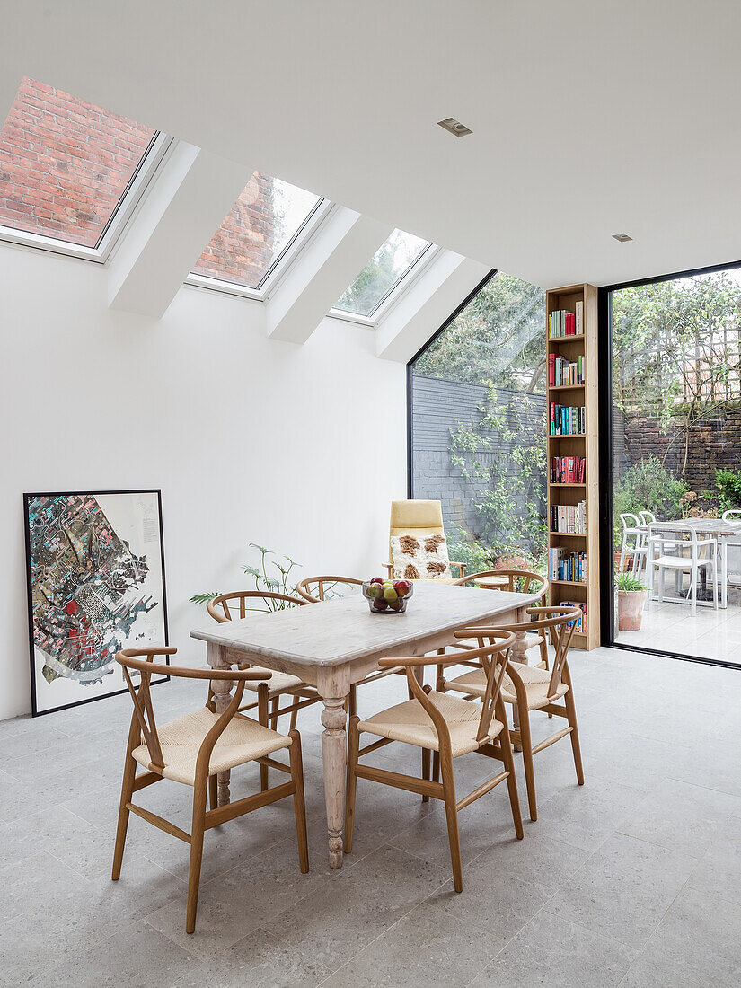 Dining area in light flooded living room with high ceiling and floor to ceiling windows