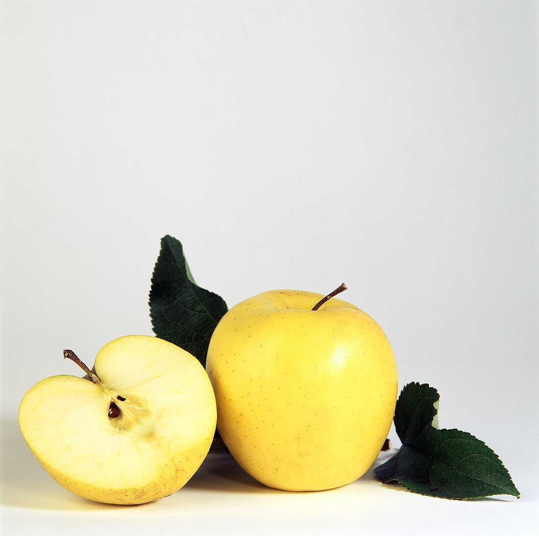 Two Golden Delicious; One Cut in Half