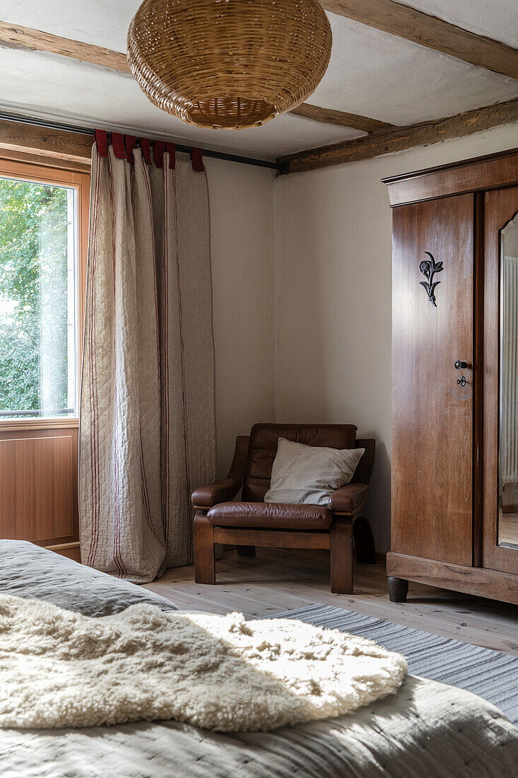 Leather armchair next to wardrobe in country style bedroom