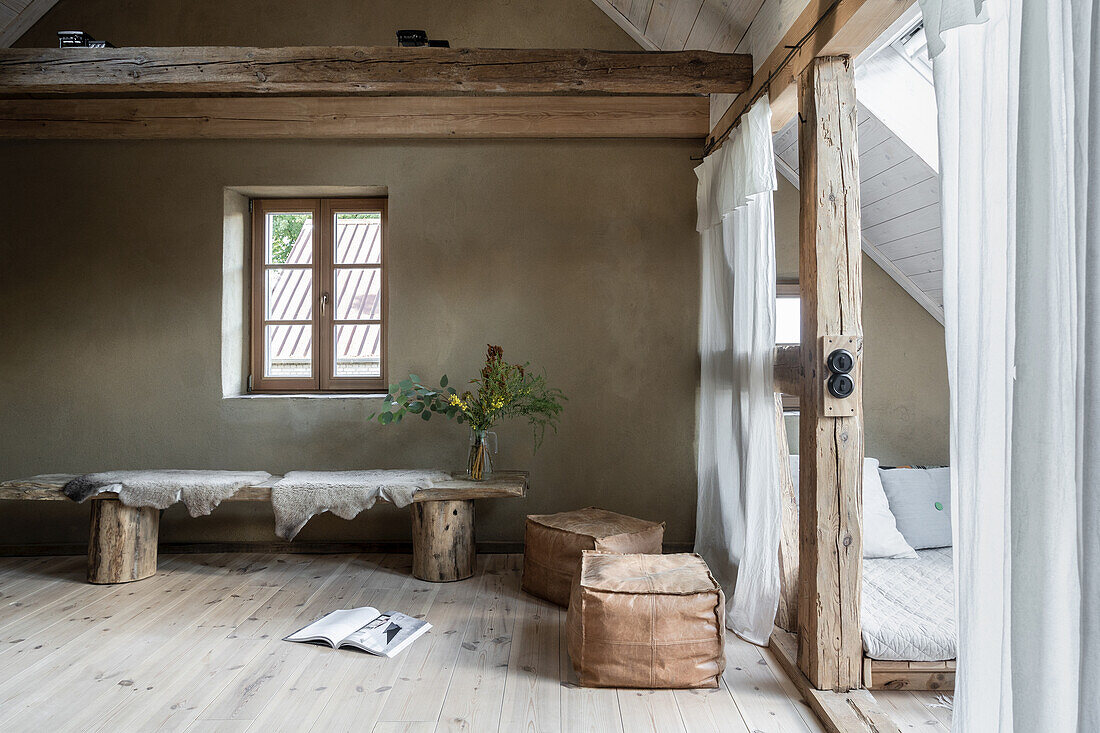 Wooden bench with sheepskin as table and leather cube, sleeping area with pitched roof in old country house