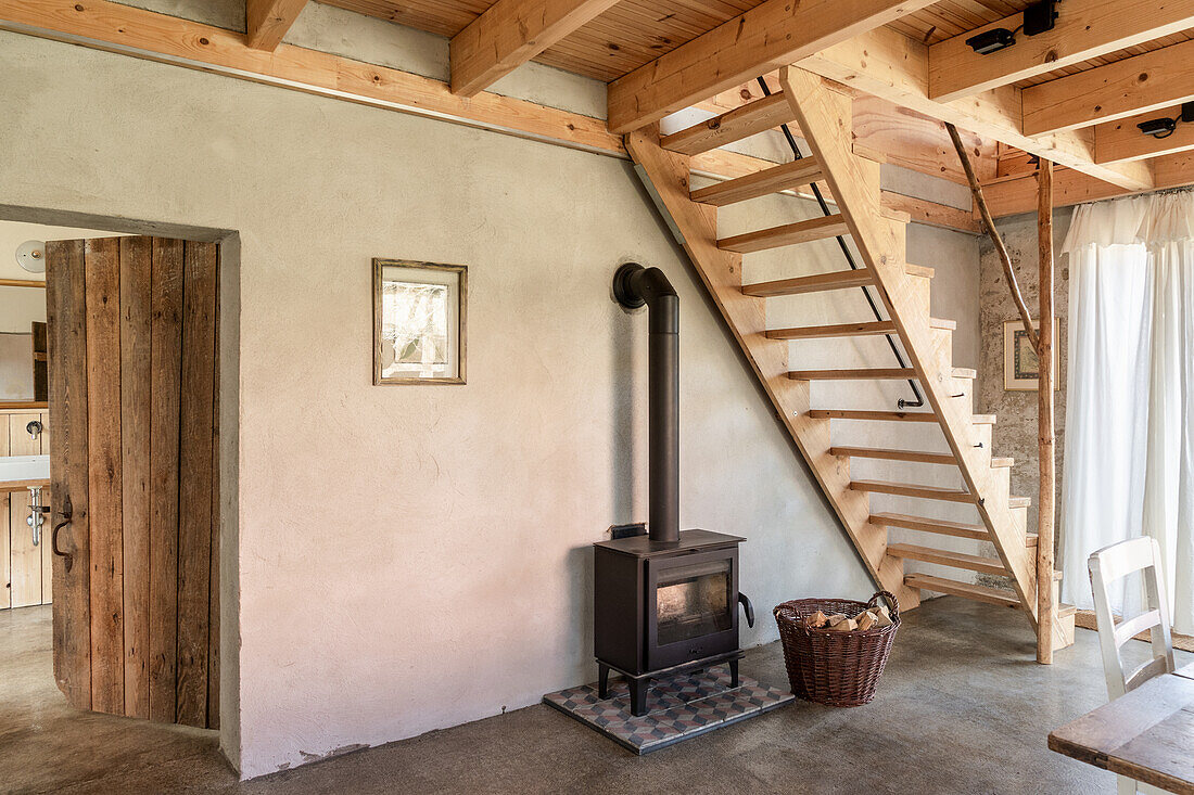 Kachelofen unter Holztreppe in renoviertem Landhaus