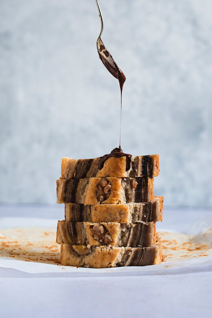 Banana bread with melted chocolate being poured over it