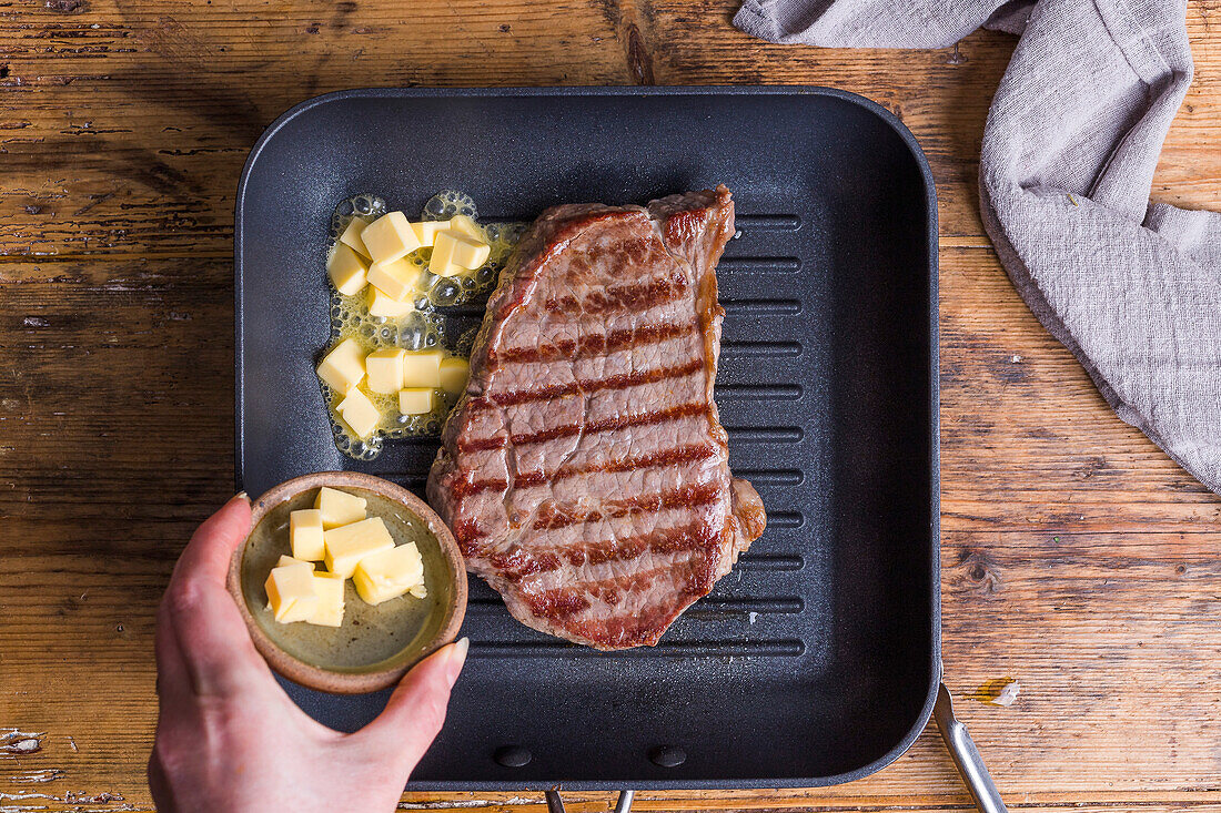 Cooking steak in a griddle pan with butter
