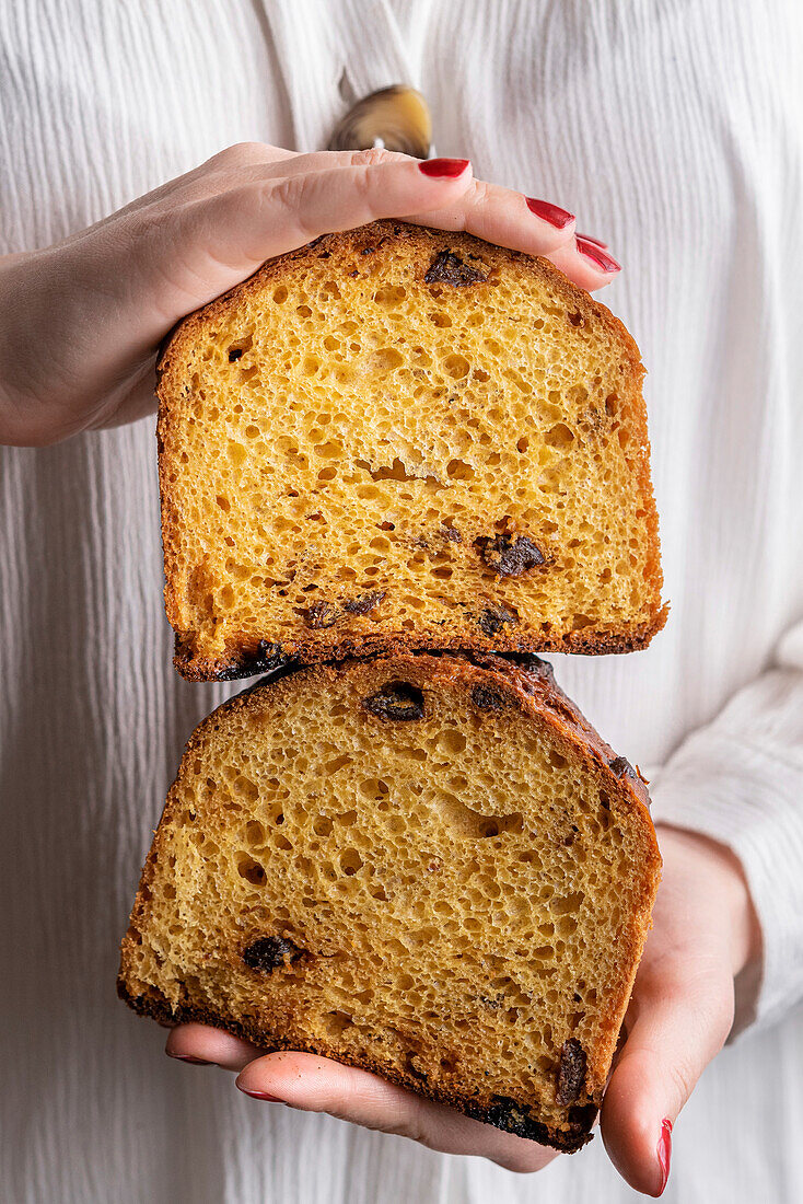 Hands holding two slices of panettone