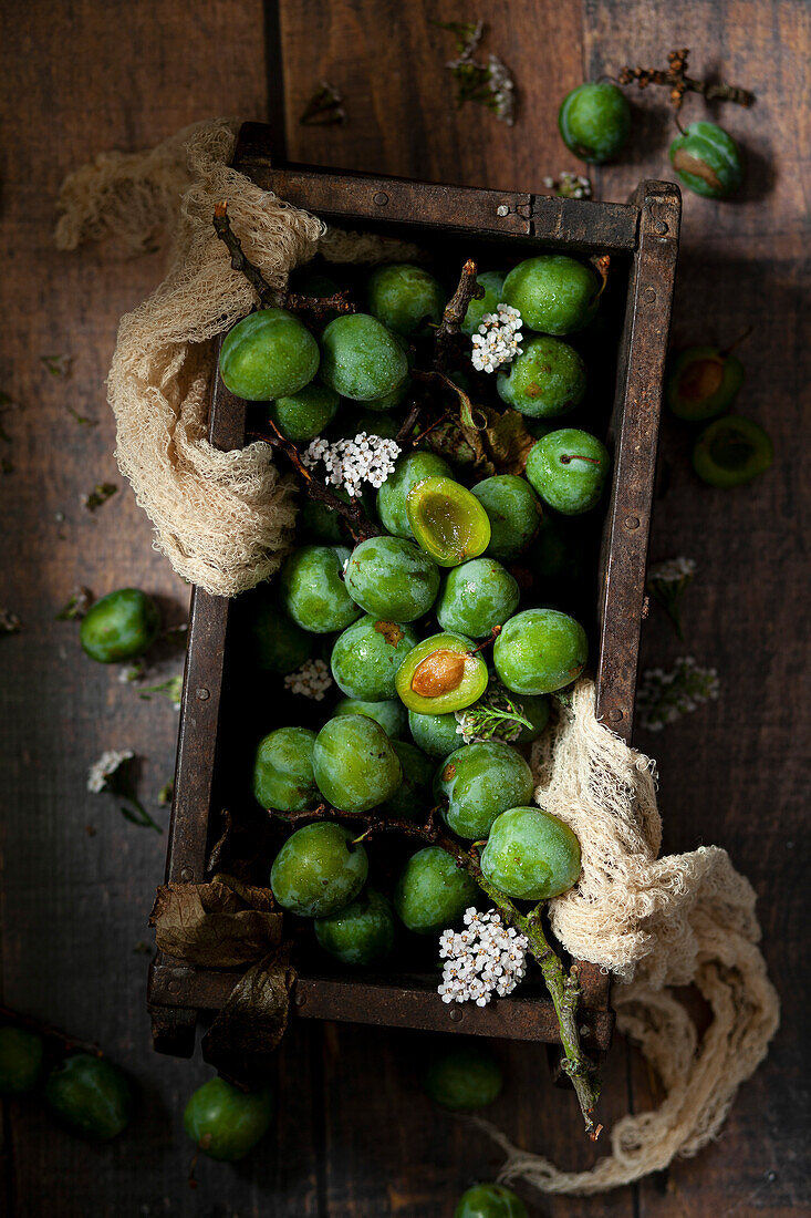Holzkiste mit frisch gepflückten grüne Pflaumen