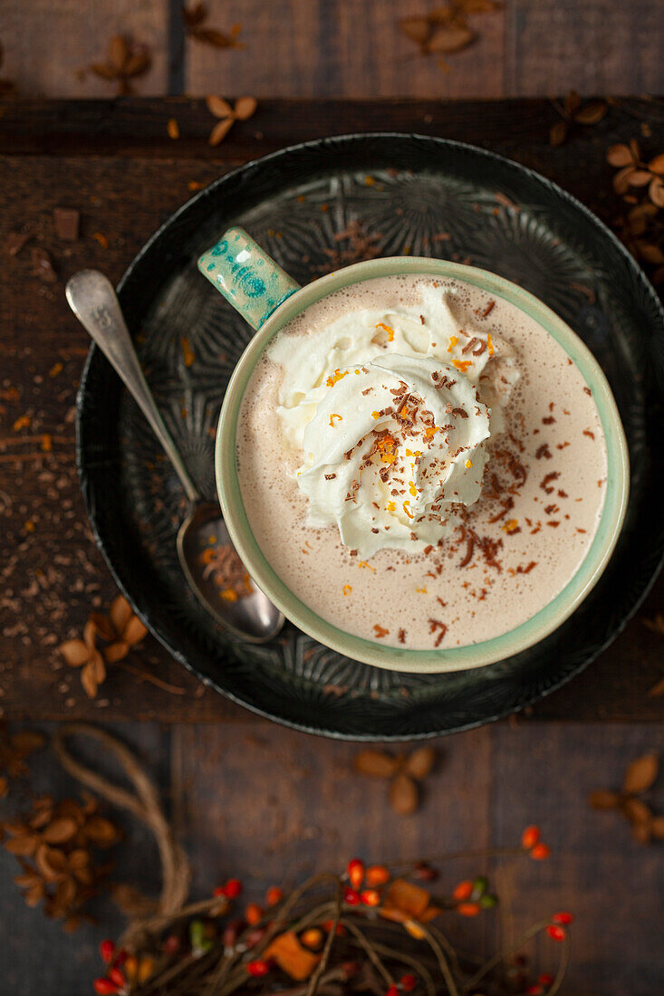 A mug of orange flavoured hot chocolate with whipped cream, orange zest and grated chocolate