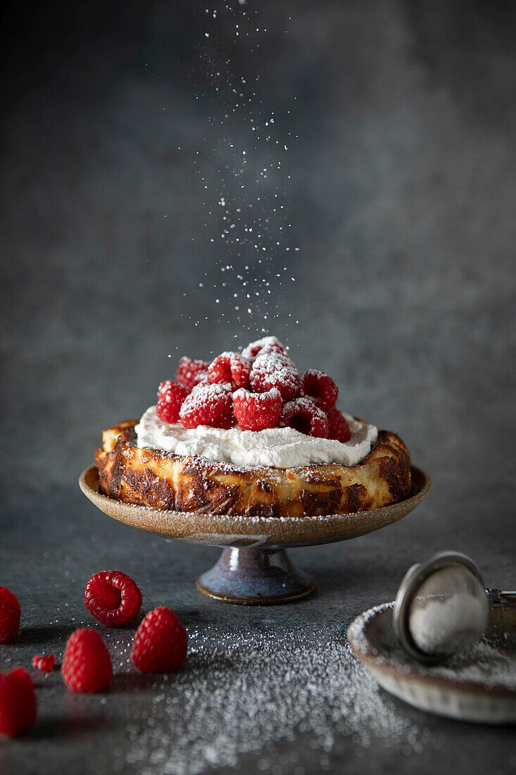 Basque Cheesecake with Whipped Cream and Raspberries on Dark Neutral Background