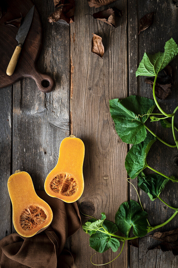 Sliced butternut squash and vines on a rustic wooden table