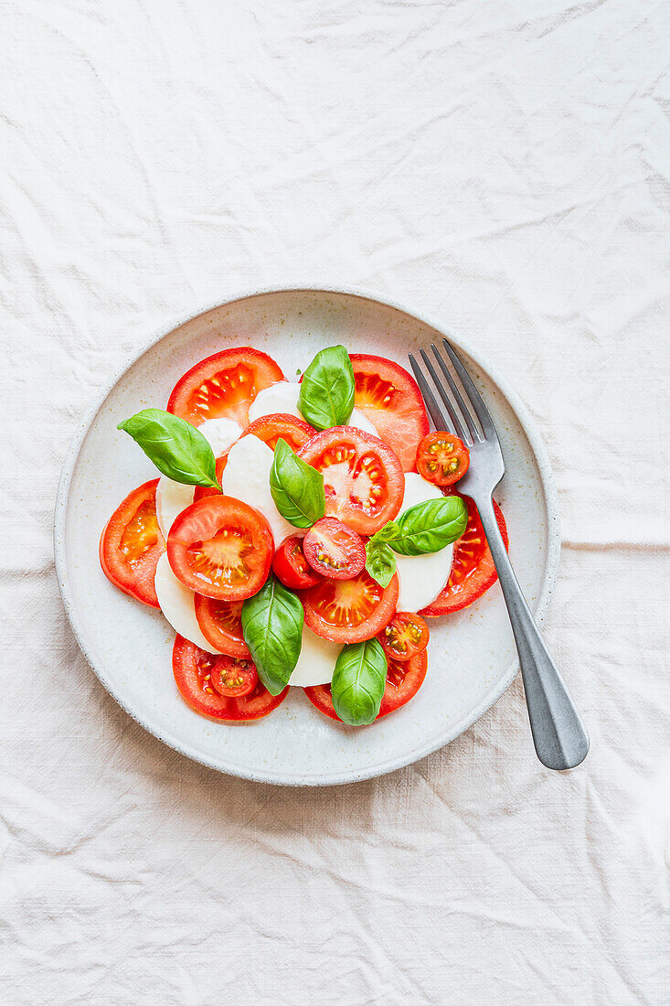Tomato, mozzarella and basil salad in a ceramic bowl, with fork