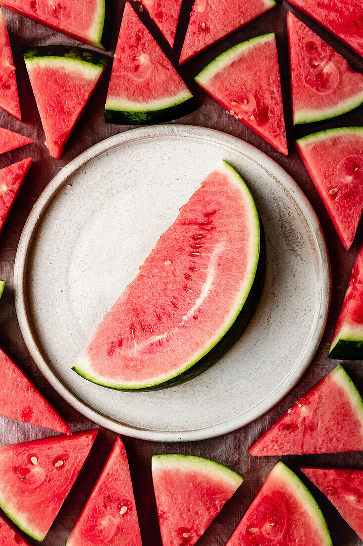 Wassermelonenspalte auf Keramikteller umgeben von Wassermelonenstücken