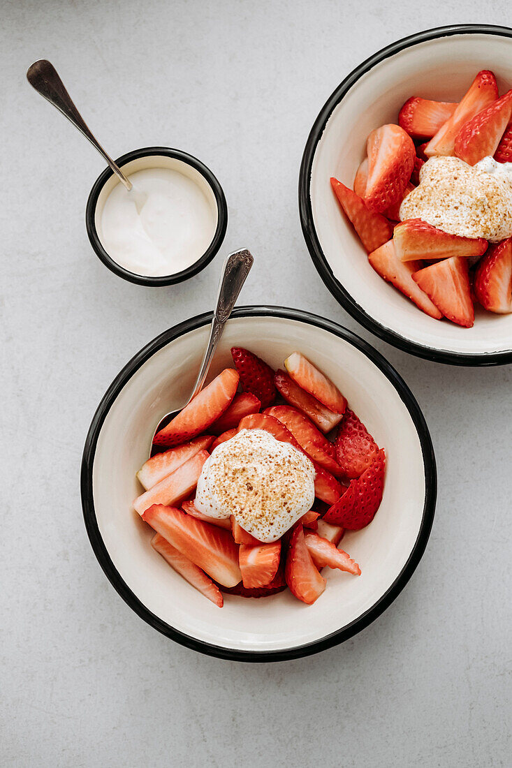 Erdbeeren mit Schlagsahne und braunem Zucker in Emailleschälchen