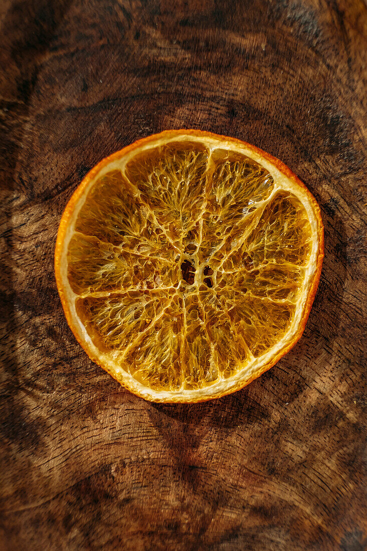 Dünne getrocknete Orangenscheibe auf Holzuntergrund