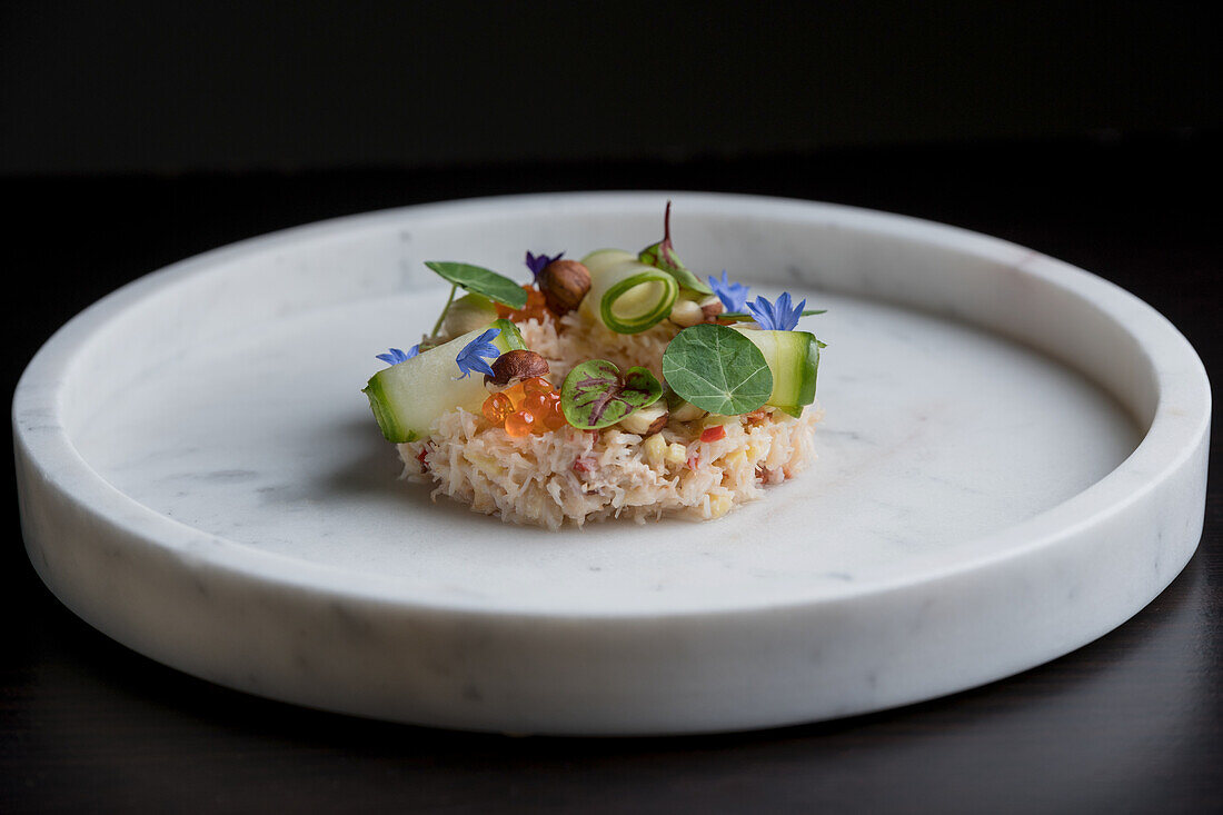 Appetizing snack with crab near decorated with cucumber rolls and caviar