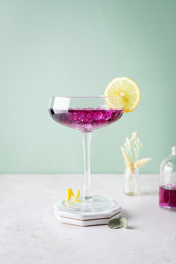 Elegantes Glas mit Brombeerlikör, Crushed Ice und Zitronenscheibe