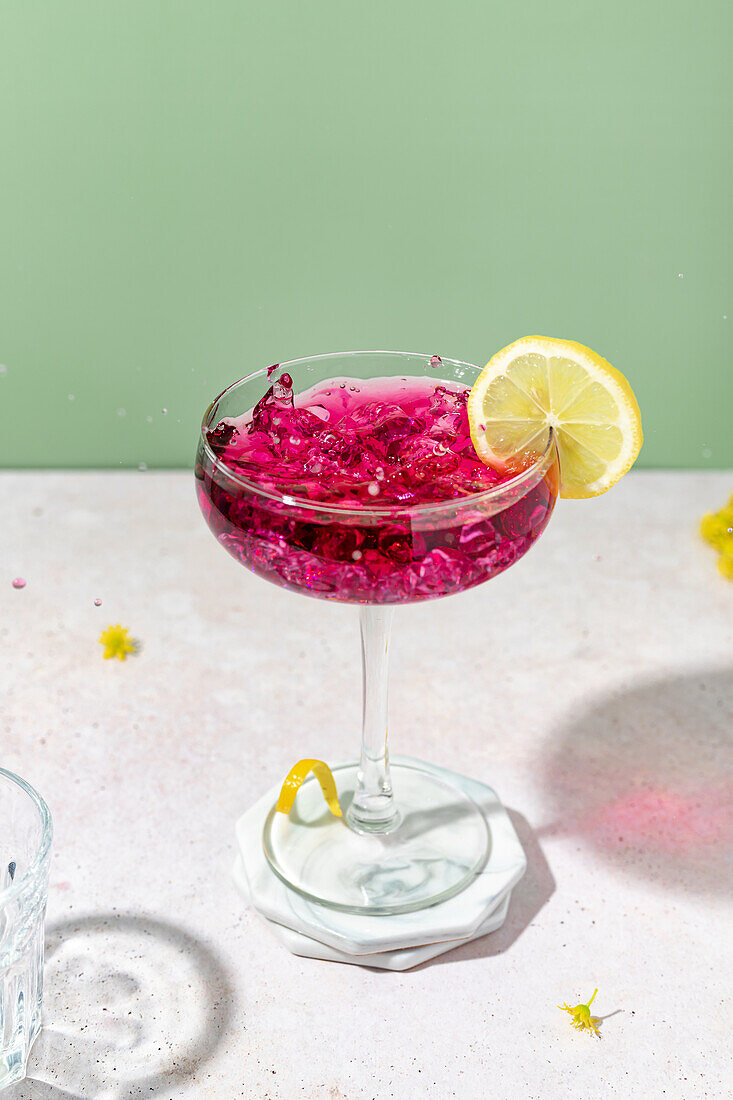 Elegantes Glas mit Brombeerlikör, Crushed Ice und Zitronenscheibe