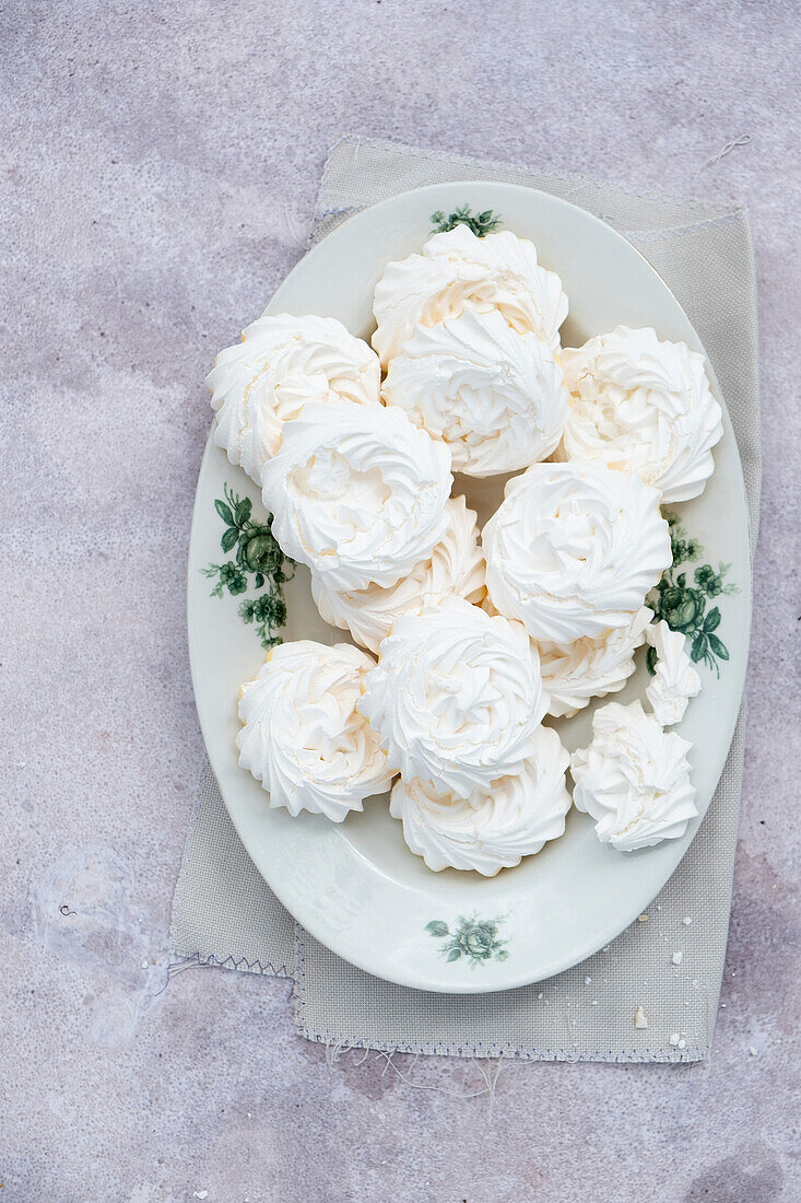 Bunch of delicious white meringue dessert placed on oval plate on gray marble table