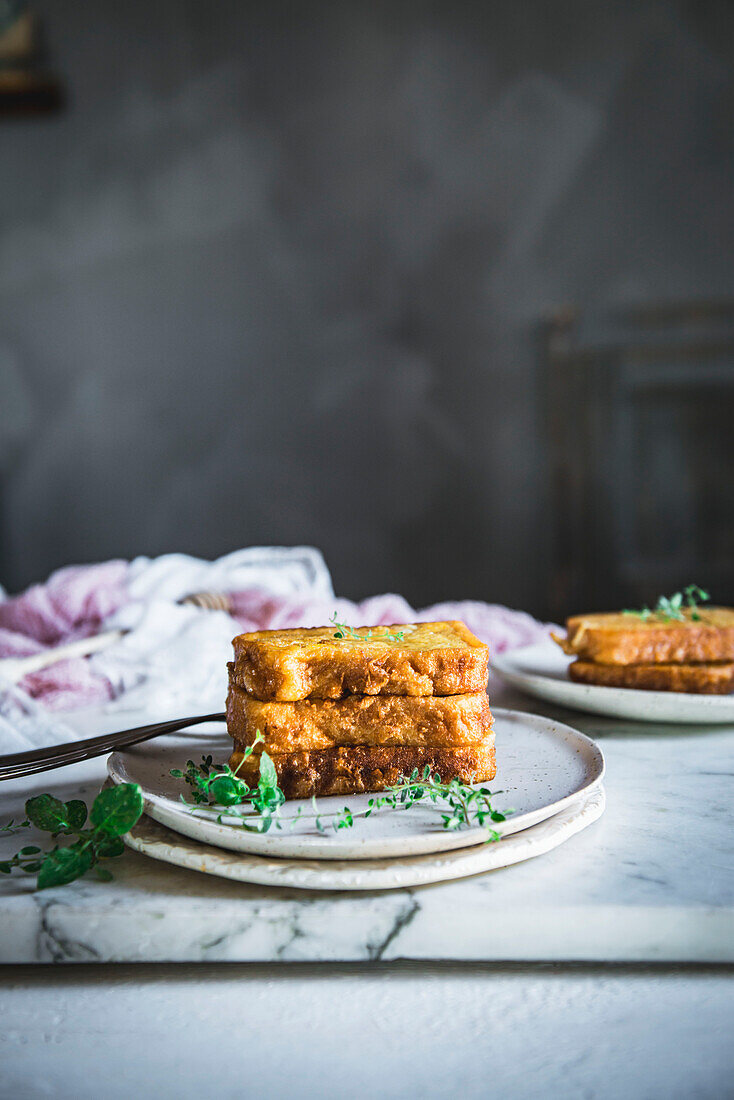 Tasty sweet fried French toasts served on plate with forks on marble table in light kitchen