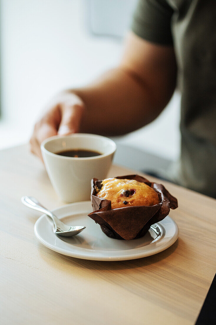 Tasse Kaffee und ein Muffin auf Tisch