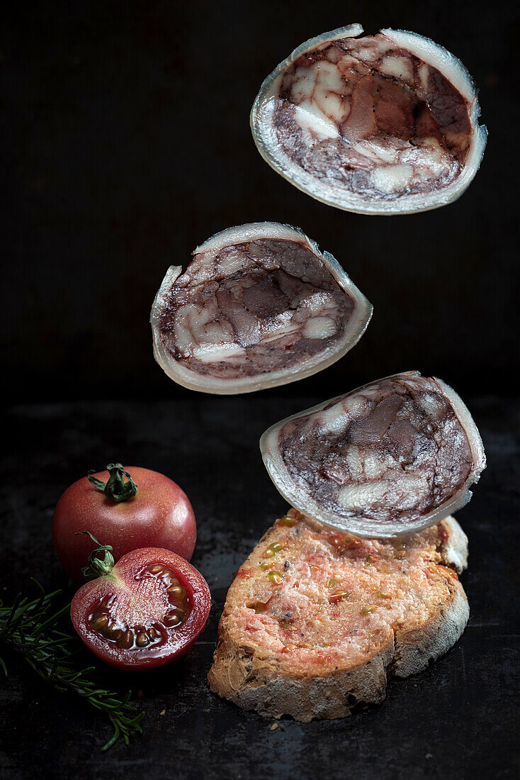 Tasty round camallot slices with pork falling on toast on table with ripe red tomatoes
