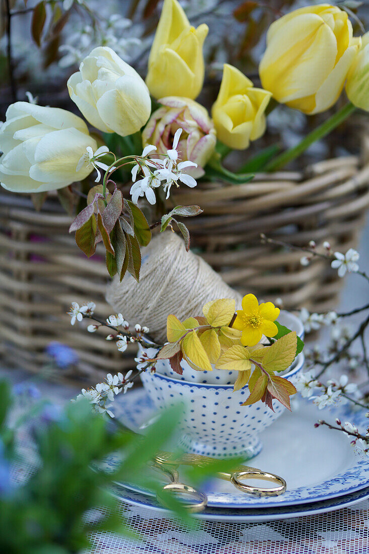 Wicker basket with spring flowers and spool of thread, bouquet of tulips