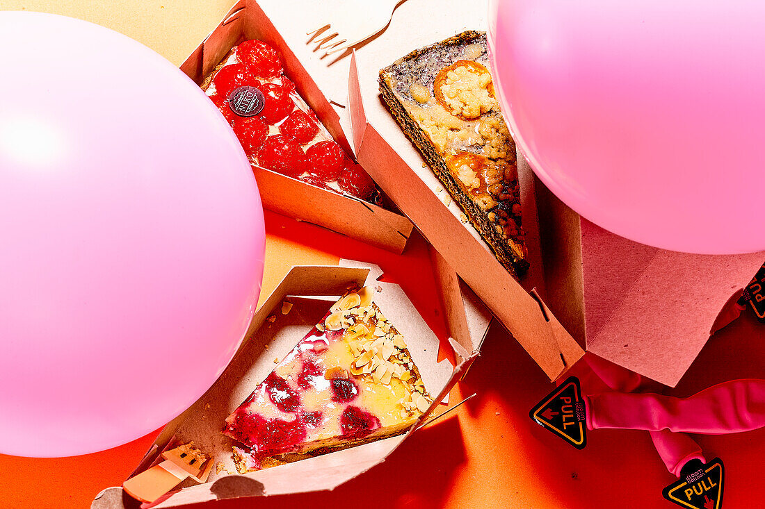 Fruchtige Kuchenstücke in Pappkartons und Luftballone für eine Party