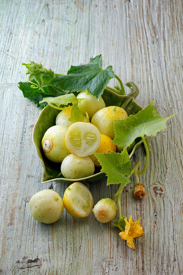 Lemon cucumbers with leaves on wooden background
